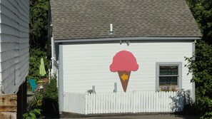 A small building with a white exterior, a single window, and a white picket fence.