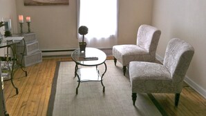 A living room with a round glass table, two armchairs, a small potted plant, and a painting on the wall. - Marine On St Croix Retreat, Unit 1 (Marine On Saint Croi)