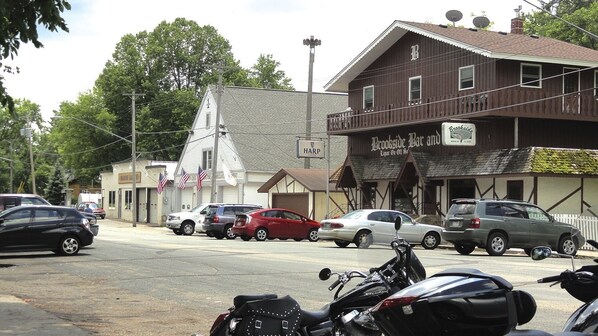 A street view with parked cars and motorcycles, a building labeled "Brookside Bar and Liquor," and a sign for "HARP."
