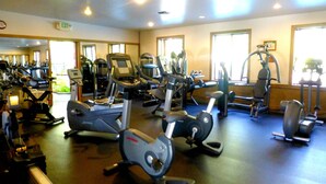A gym with various exercise equipment, including treadmills, ellipticals, and weight machines.