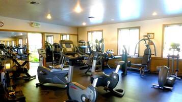 Une salle de sport équipée de divers appareils d’exercice, notamment des tapis de course, des vélos elliptiques et des appareils de musculation.