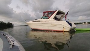 A white boat with a red stripe and a canopy, docked on calm water. - YACHT 33'~FREE KAYAK  (Key Largo)