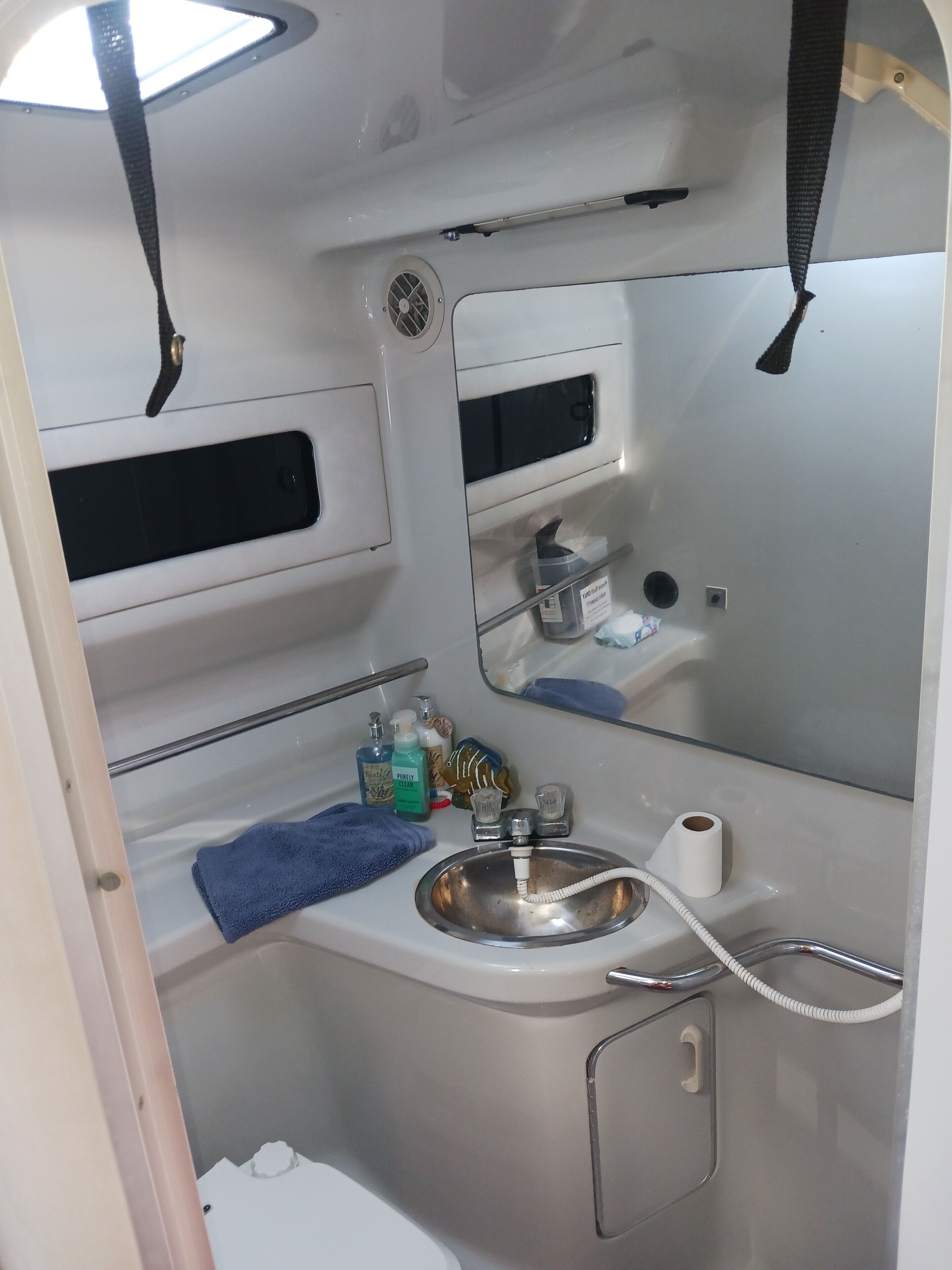 Une petite salle de bain comprenant un lavabo, un miroir et des étagères de rangement.