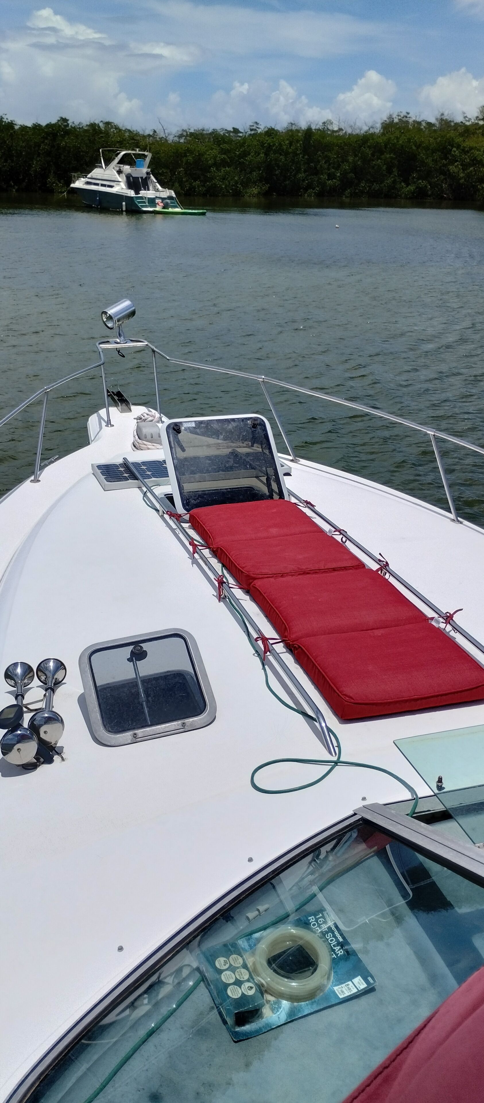 Un bateau doté d’une zone avec des coussins rouges, d’un volant et d’une petite fenêtre.