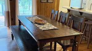 A wooden dining table with chairs, a placemat, and a bowl.