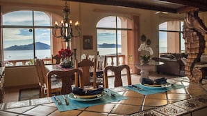 A dining area with a view of the sea, a chandelier, and a seahorse sculpture.