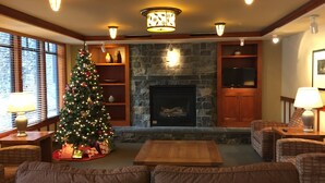 A cozy living room with a fireplace, a Christmas tree, and comfortable seating. - Village Top Floor Lincoln House - Great 2 Bedroom With View of Mammoth Mountain  (Mammoth Lakes)
