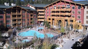 A multi-story hotel with a pool area, wooden balconies, and a mountainous backdrop. - Village Top Floor Lincoln House - Great 2 Bedroom With View of Mammoth Mountain  (Mammoth Lakes)