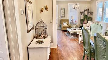 A cozy living room with a white console table, a green armchair, and a wooden floor.