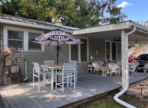 A covered patio with a table and chairs, a decorative umbrella, and a small garden area.