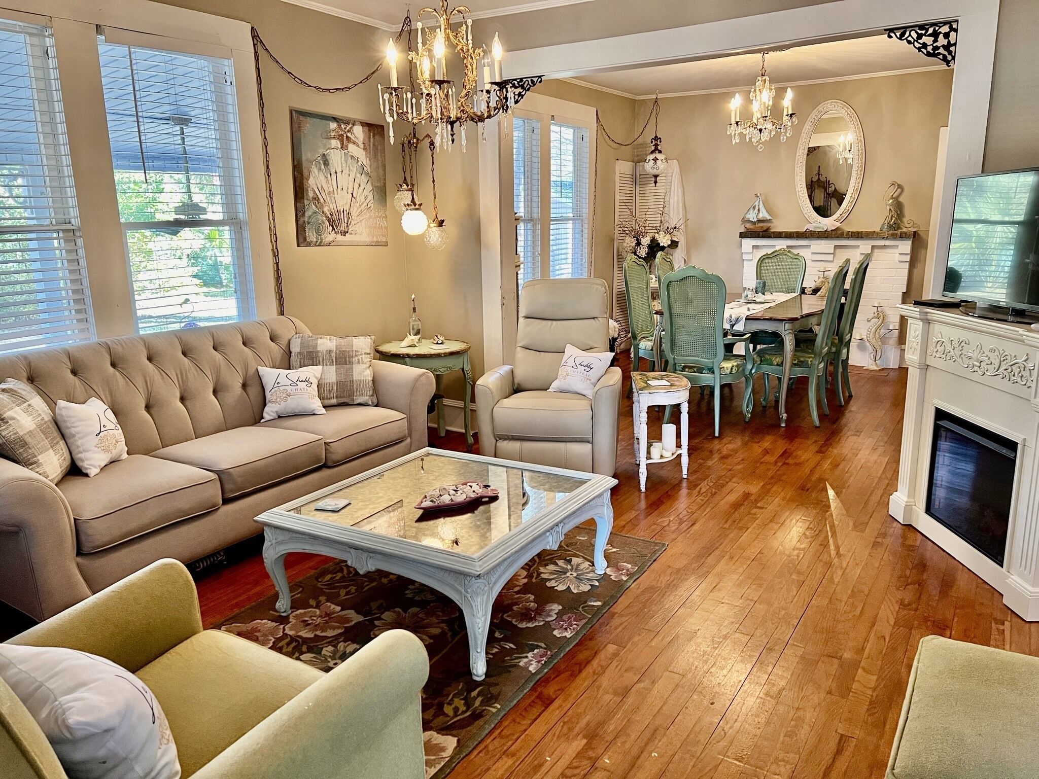A living room with a sofa, armchairs, a coffee table, and a fireplace. There is a dining area with a table and chairs.
