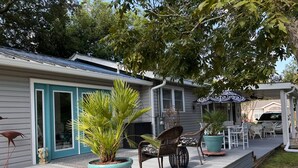 A covered outdoor area with potted plants, wicker chairs, and a small table. - Stylish Coastal Escape | 3BR Shabby Chic + Optional Cottage, Walk to Beach & Fun (Gulfport)