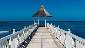 Un muelle que conduce a un pabellón con vista al océano.