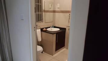 A small bathroom with a toilet, sink, and mirror.