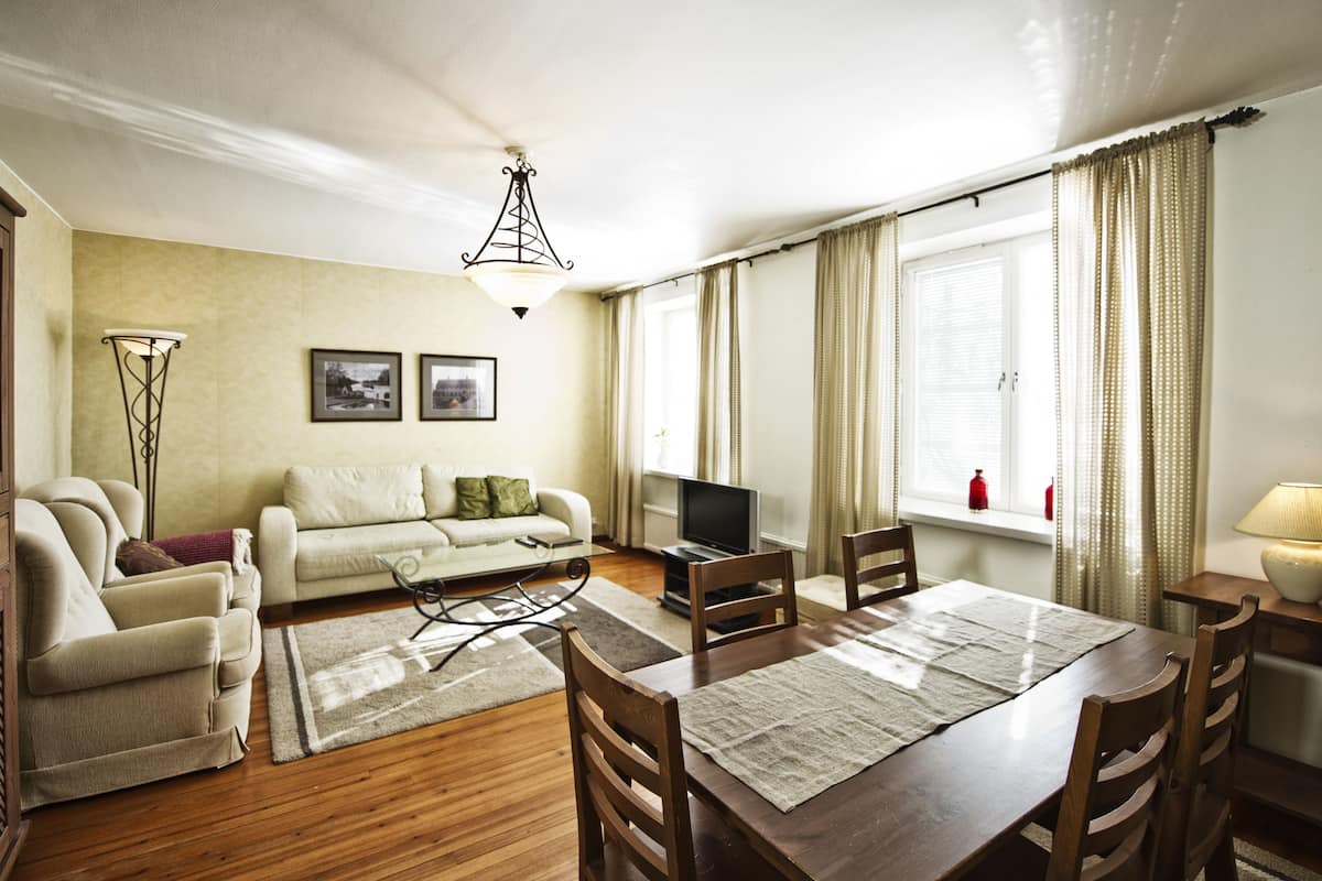 Een woonkamer met een bank, televisie, eettafel en stoelen.