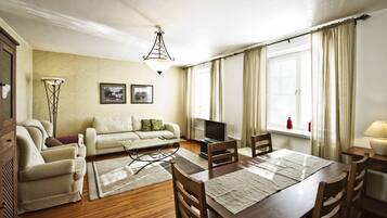 A living room with a sofa, TV, dining table, and chairs.
