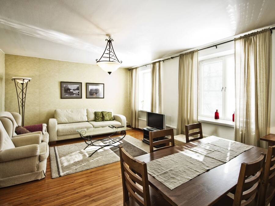 A living room with a sofa, TV, dining table, and chairs.