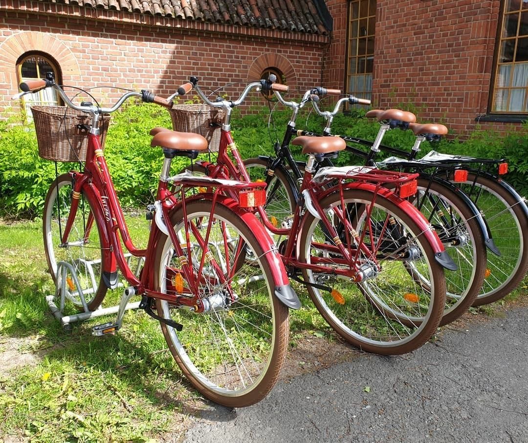 Drie fietsen staan geparkeerd voor een gebouw met een bakstenen gevel en een pannendak.