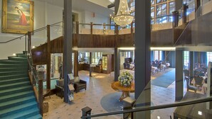 A spacious lobby with a grand staircase, a chandelier, and a large painting. - Hotelli Vanajanlinna (Hameenlinna)