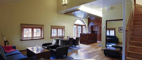 A spacious living area with a wooden staircase, a dining table with chairs, and a blue sofa.