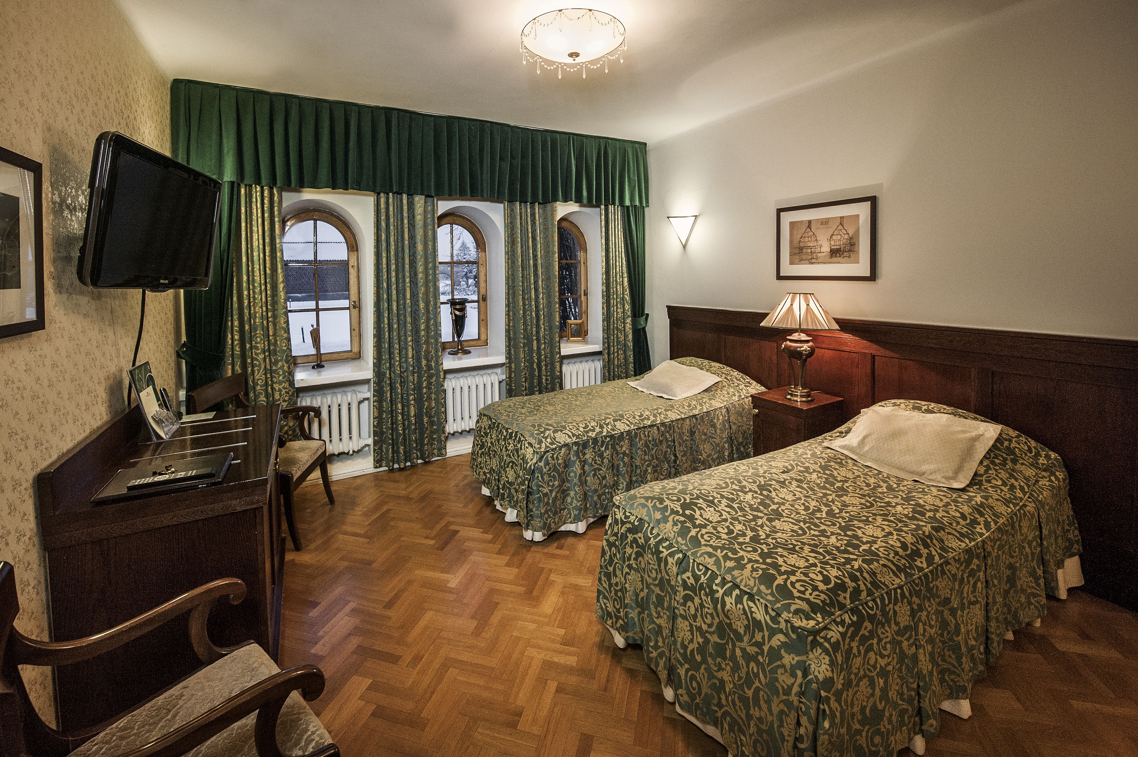 A room with two beds, a desk, a television, and a window with curtains.