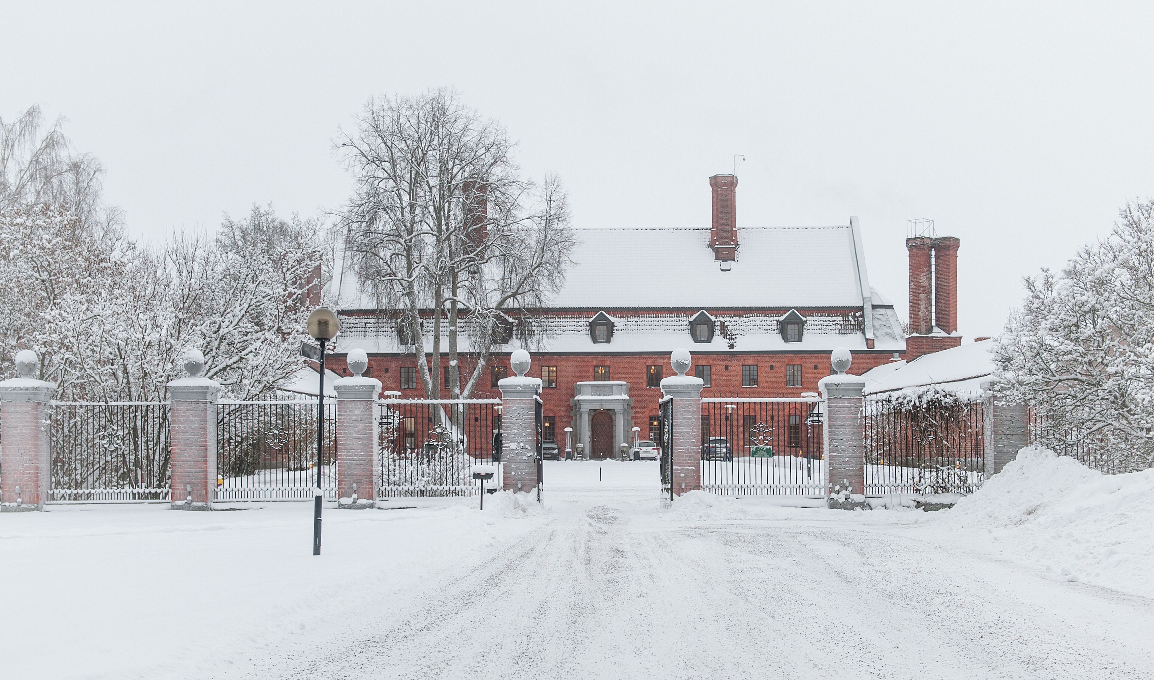 A large brick building with a snow-covered roof and a gated entrance.