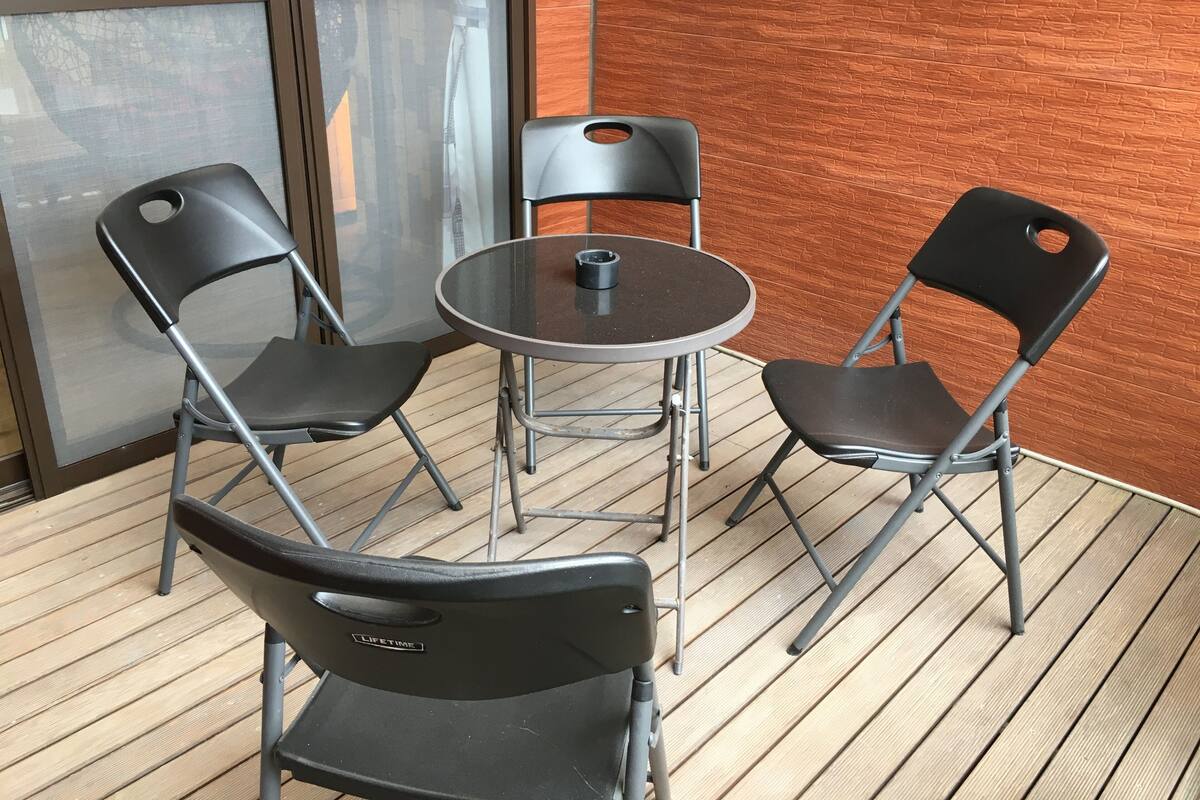 A small round table with two black chairs, a coffee cup, and a window with a view of buildings.