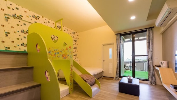 Habitación pensada para niños, con un área de juegos verde, un pequeño sofá y ventana con vistas.