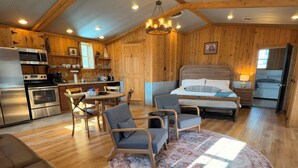 A cozy cabin-style room with a bed, a dining table, and a kitchen area. - Cabin and Private Basketball Gym, Hocking Hills (Logan)