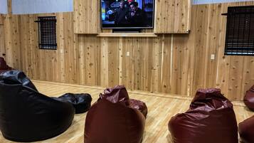 A room with a wooden wall, a mounted TV, and several bean bags.