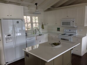 A kitchen with white cabinets, a refrigerator, a microwave, an oven, and a sink.
