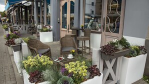 Un espace extérieur aménagé avec des meubles en osier et des jardinières contenant différentes sortes de fleurs.