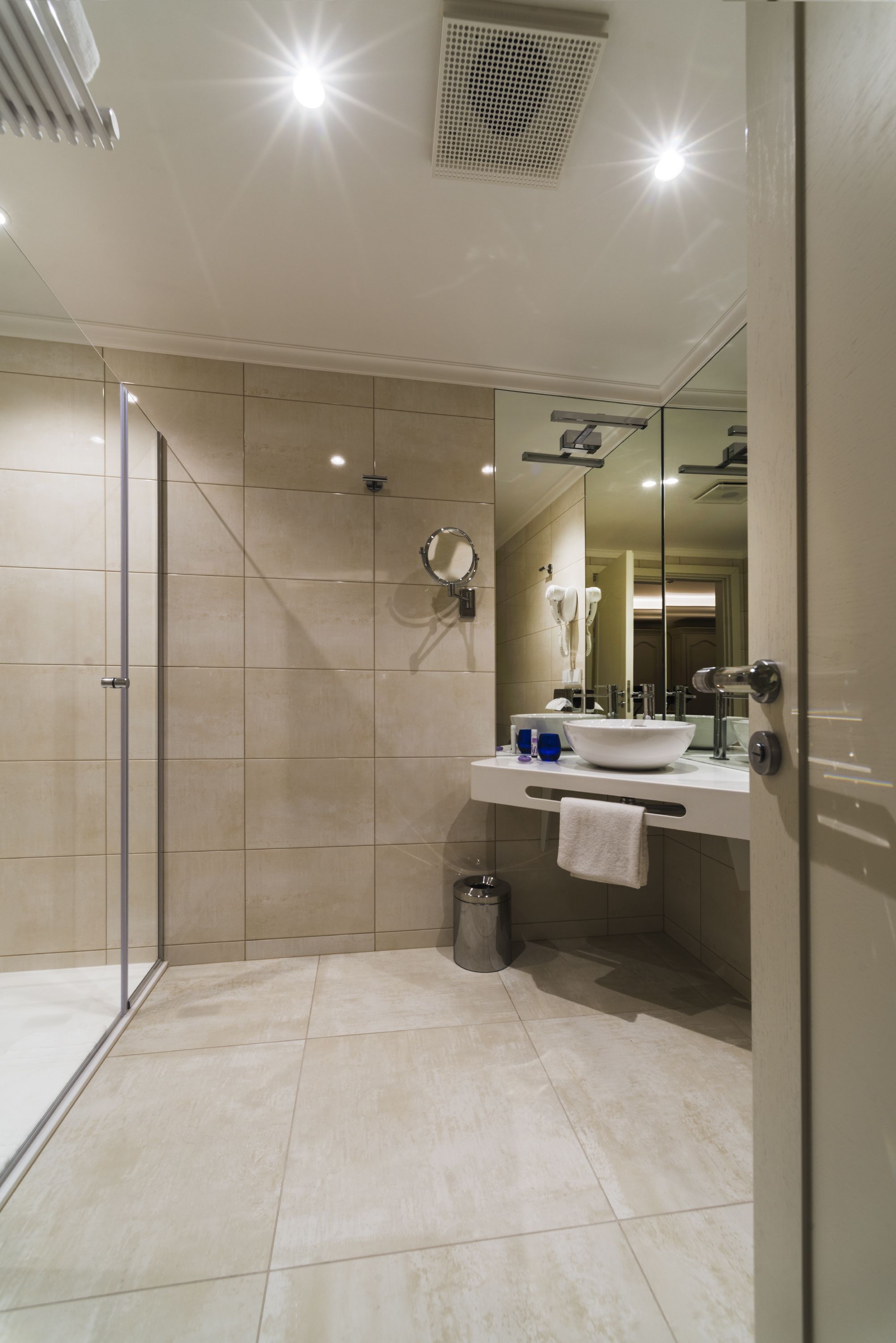 A modern bathroom with a glass shower enclosure, a white sink, and a large mirror.