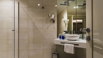 Un baño moderno con cabina de ducha de vidrio, un lavabo blanco y un espejo grande.