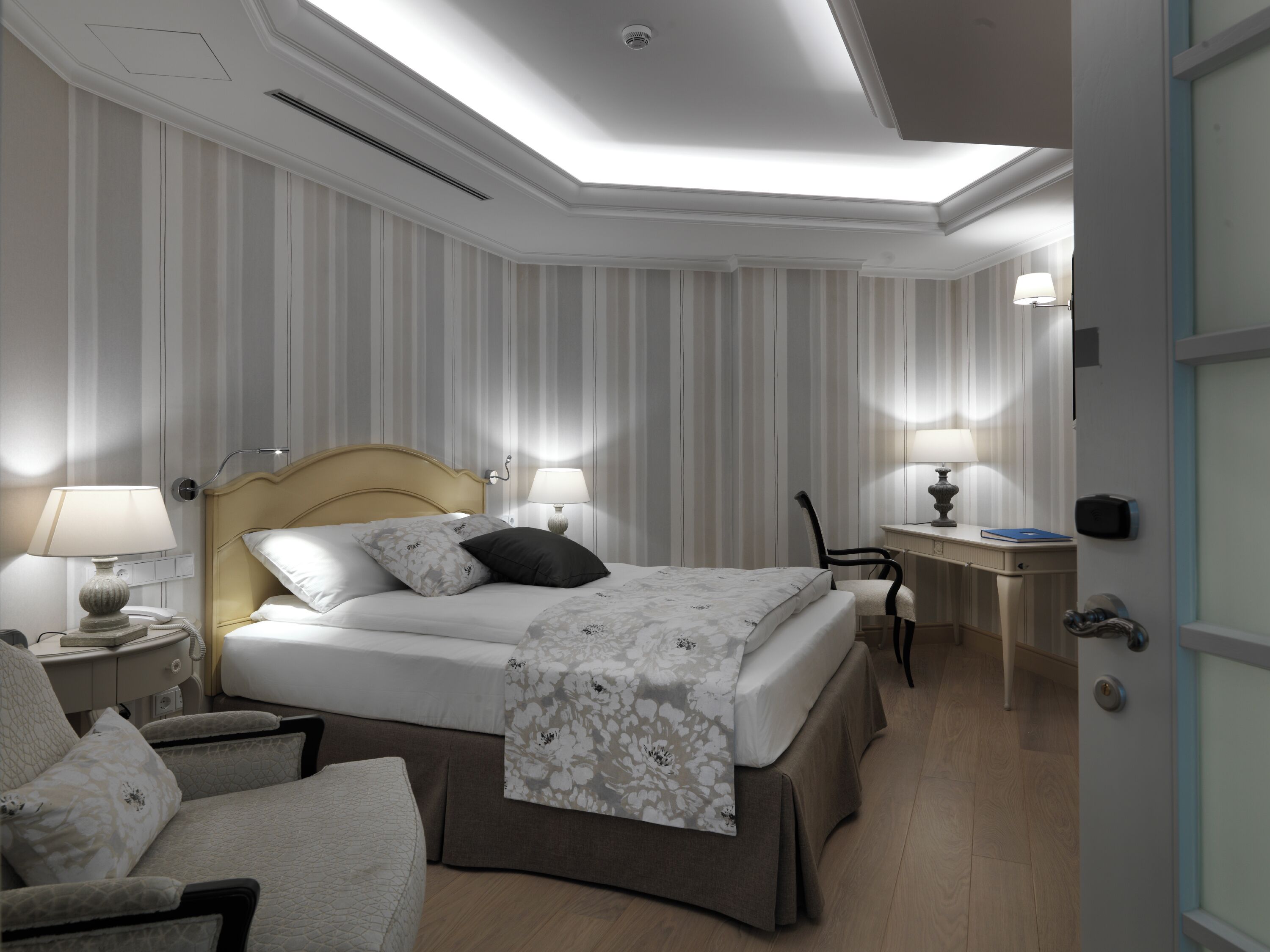 Een hotelkamer met een bed, nachtkastjes, een stoel en een bureau met een lamp.