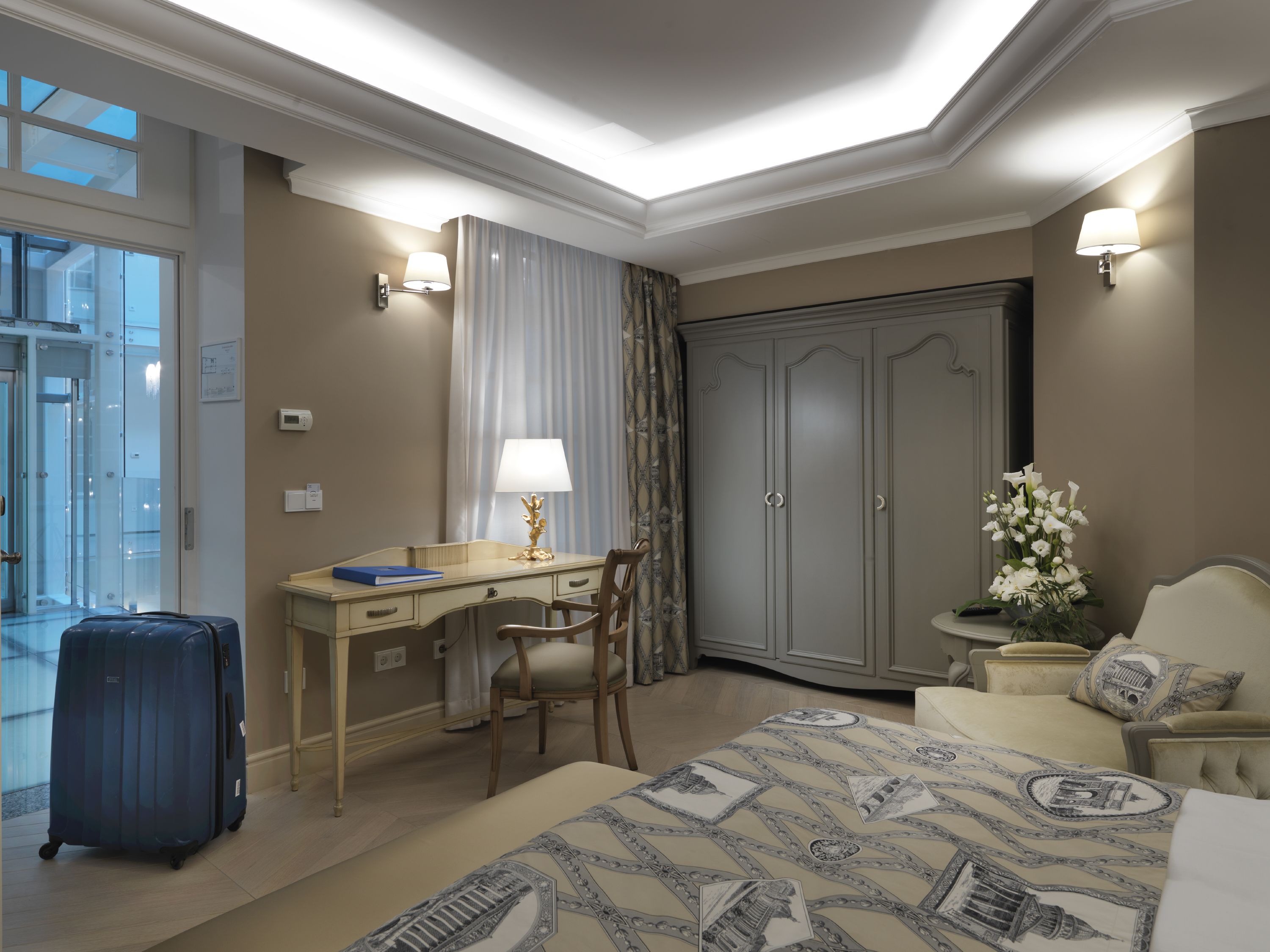 Habitación de hotel con escritorio, silla, cama, armario y vistas al exterior.