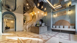 Un hall d’hôtel comprenant un comptoir d’accueil, un escalier et un espace détente.