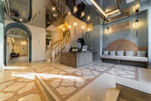 A hotel lobby with a reception desk, a staircase, and a seating area. - Relais Le Chevalier (Riga)