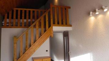 Eine Holztreppe führt zu einem Erkerbereich mit einer weißen Wand und einer Tür.