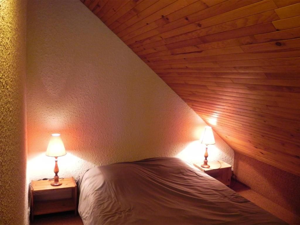 Ein kleiner, gemütlicher Raum mit schrägen Wänden und zwei Nachttischlampen.