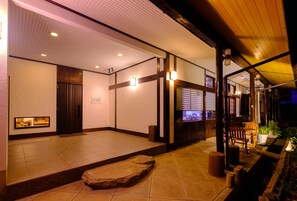 A traditional Japanese-style interior with tatami flooring, a reception desk, and a television screen. - Good Stay Mizuho (Usa)