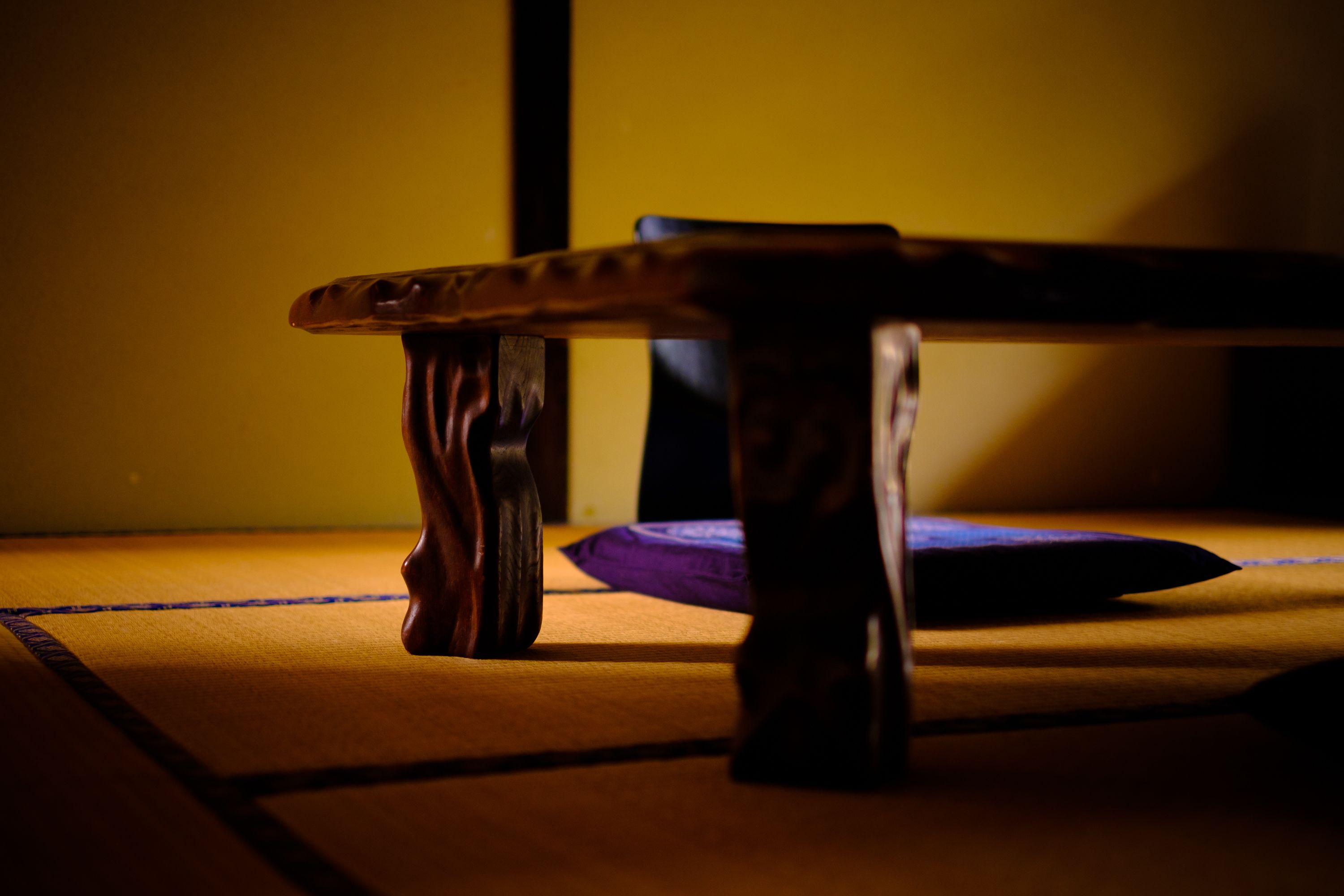 Ein Holztisch mit Kissen auf einem Tatami-Boden.