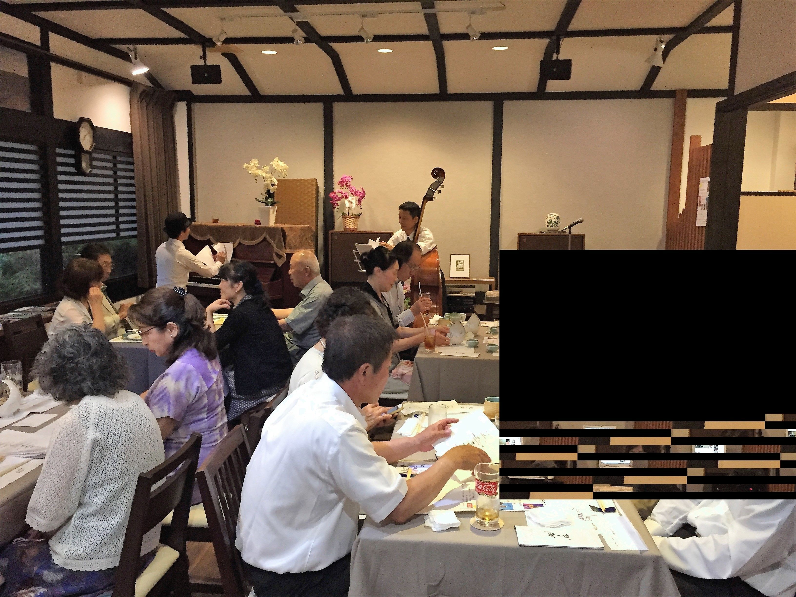 Un restaurante con mesas dispuestas para comer, un reloj en la pared y una persona tocando la guitarra.