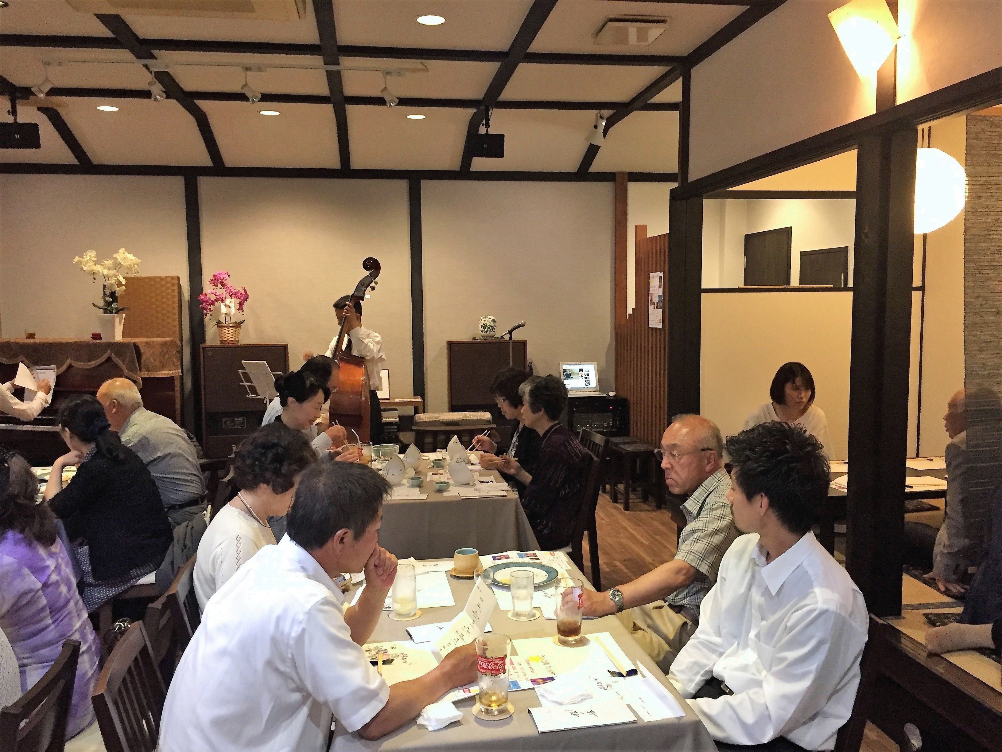 A dining area with tables set for a meal, a musician performing, and a laptop on a table.