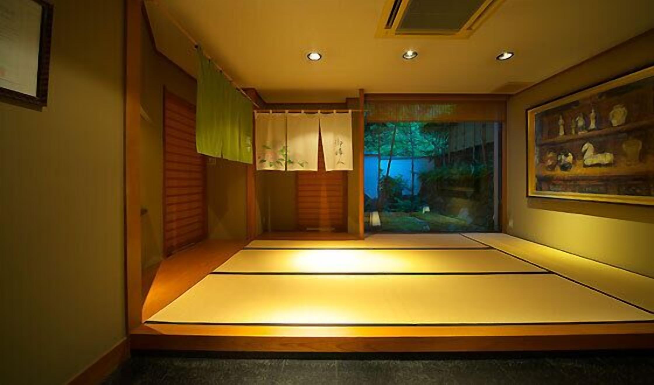 A tatami mat room with a view of a garden through a sliding door.
