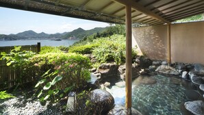 Un jardín tranquilo con una fuente de agua cristalina, rodeado de exuberante vegetación y vistas a montañas lejanas.