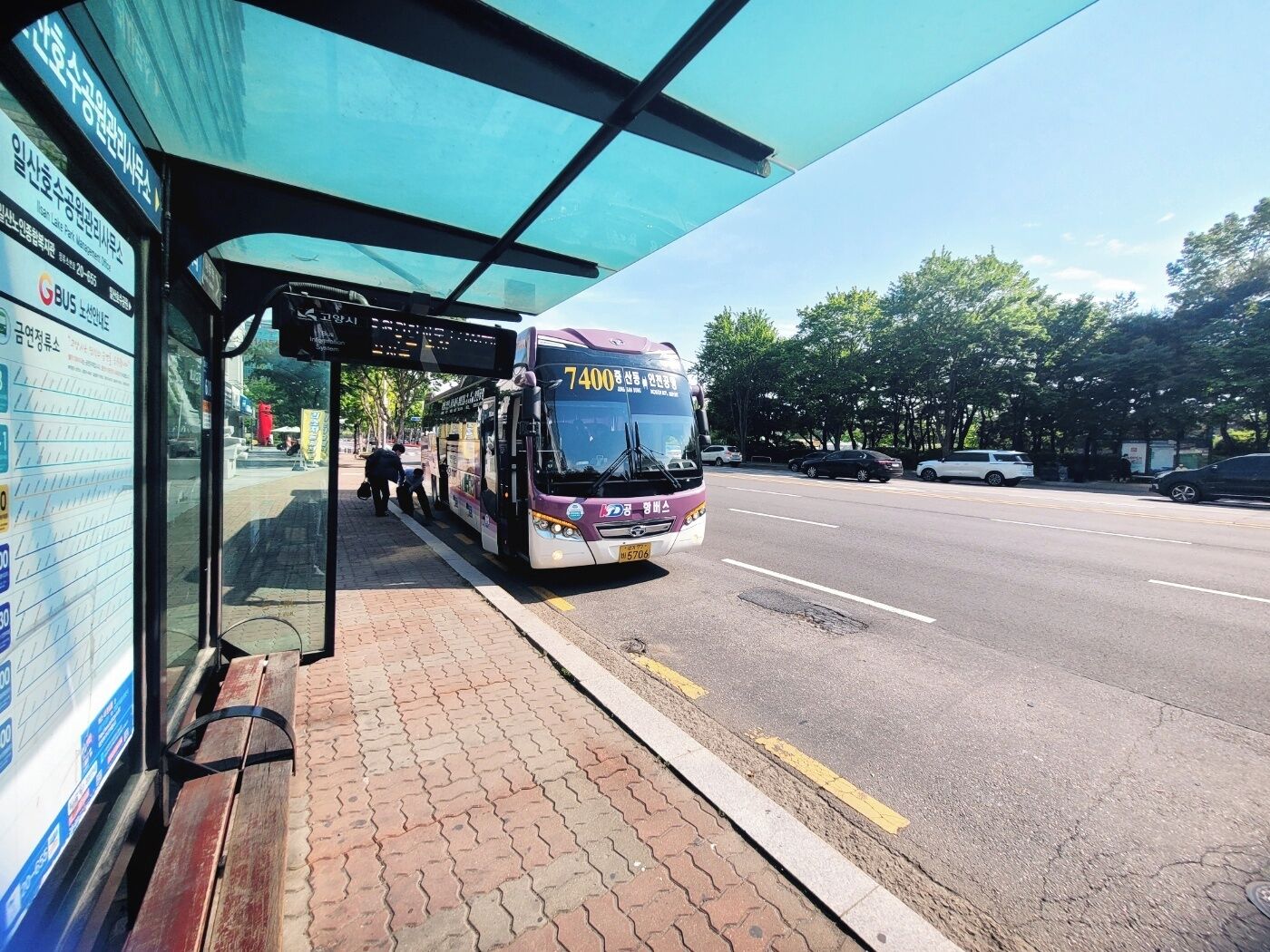 A bus stop with a shelter, a bus, and a paved sidewalk.