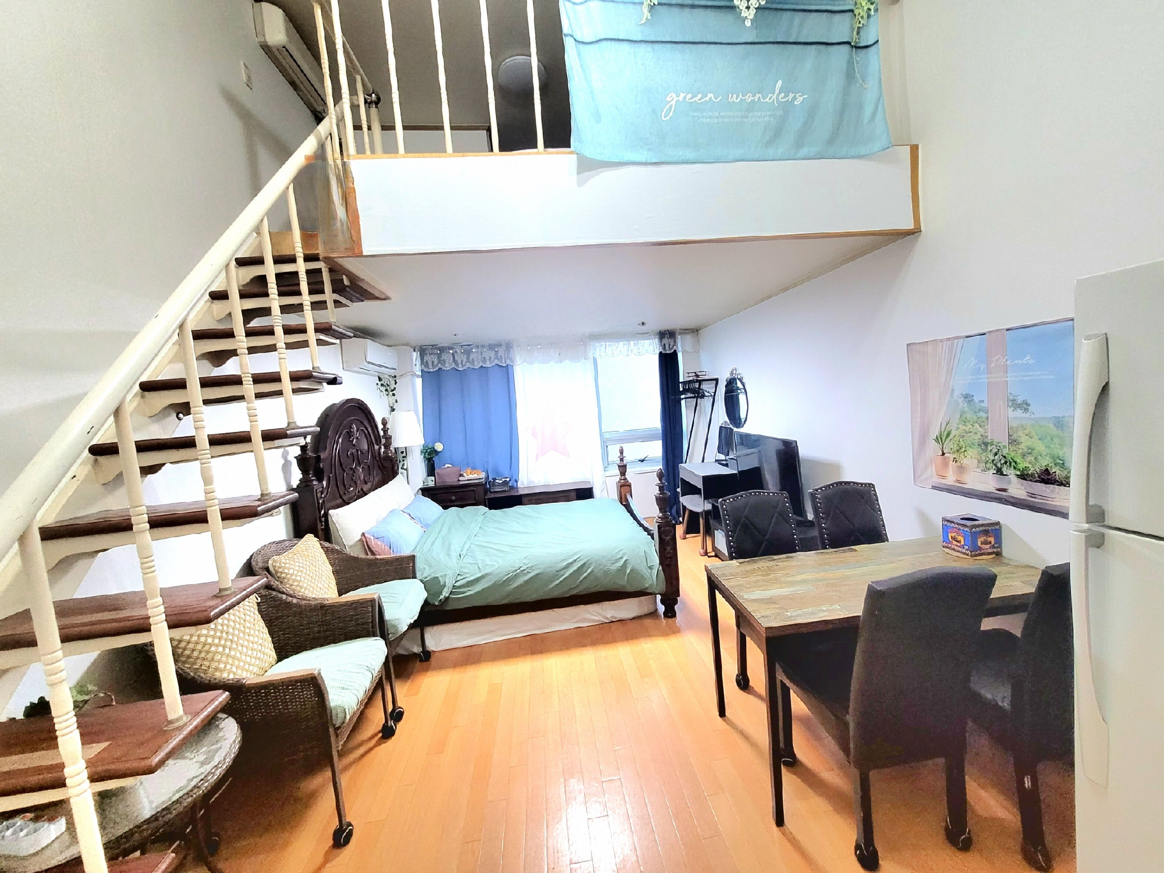 A loft-style bedroom with a staircase, a bed, a desk, and a dining area.