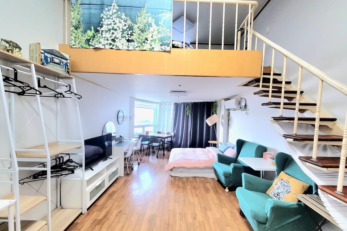 Un appartement moderne de style « loft », doté d’une mezzanine, de planchers en bois, d’un coin repas et d’un escalier.