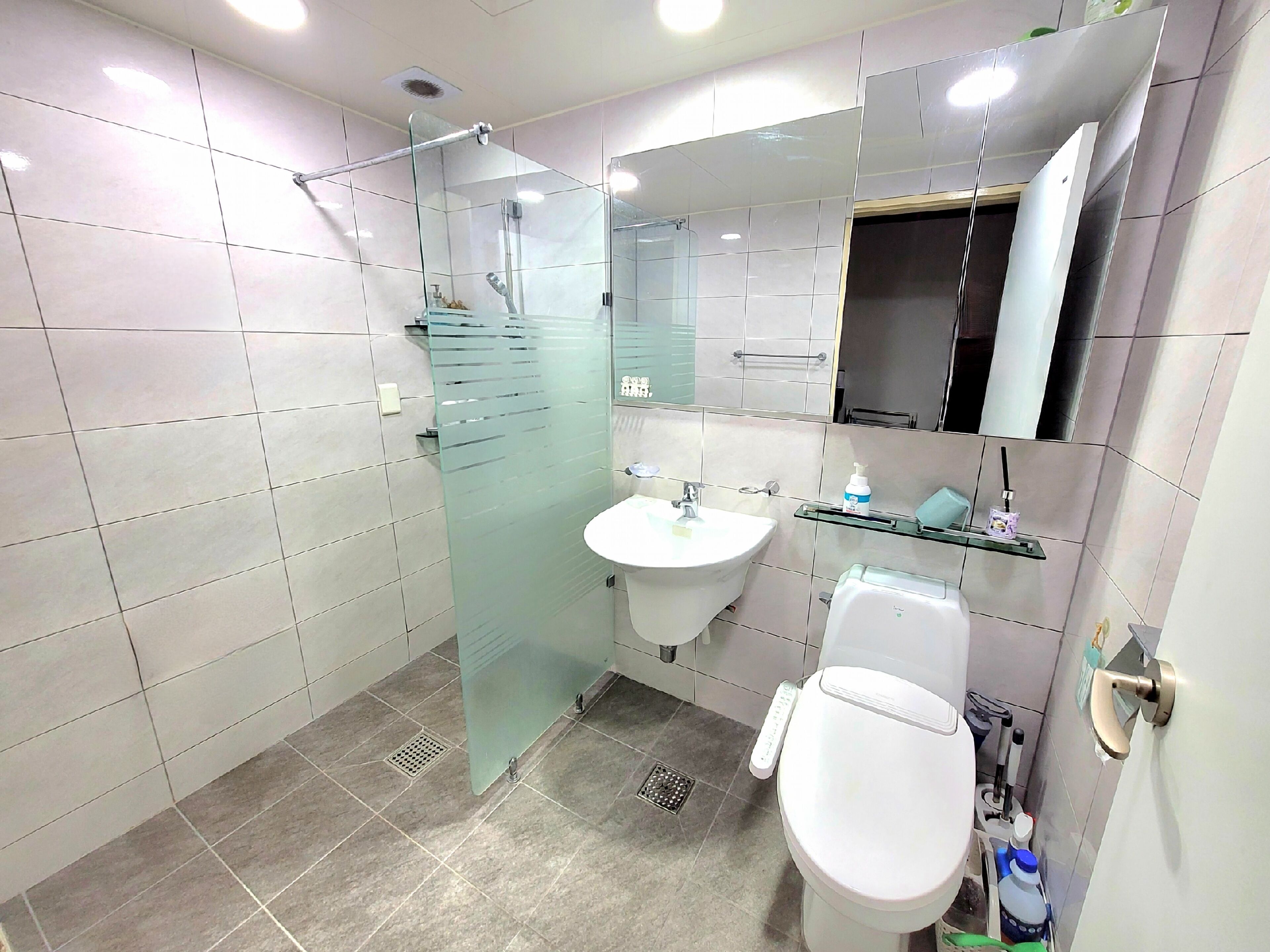 A modern bathroom with a glass shower enclosure, a white sink, and a toilet.
